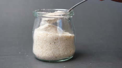 psyllium seeds in a glass container on table