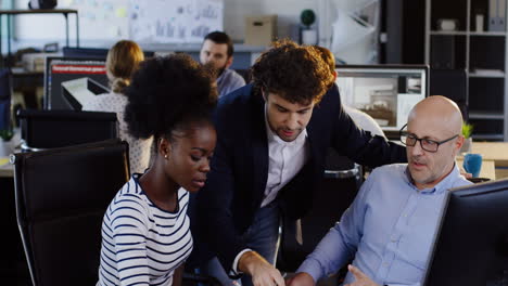 Multiethnic-office-employees-talking-about-business-project-while-working-on-the-computer-in-the-office