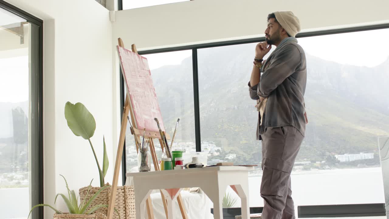 Etter å ha plassert penselen ved staffeliet, inspiserer en indisk kunstner et lerret og planlegger strøk i et studio, med kopieringsområde