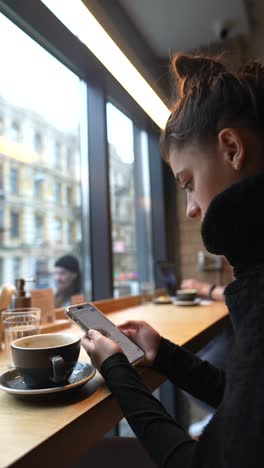 young woman enjoying coffee and phone in a cafe