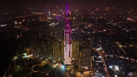 aerial of landmark 81, the tallest skyscraper in ho chi minh city (saigon), vietnam, illuminated against the night sky. the tower stands majestically, surrounded by a cityscape and bustling streets.