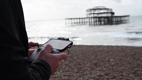 Control-Remoto-Con-Teléfono-Para-Volar-Un-Dron,-Brighton-Beach,-Sussex