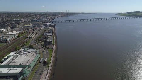 High level drone footage flying towards Tay Road Bridge, Dundee, Scotland with V-A museum and Riverside Drive on left and River Tay on right on beautiful blue sky sunny day.