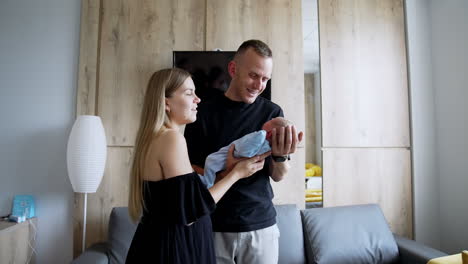 caucasian parents hold their newborn son. caring couple talking and smiling to their little kid.