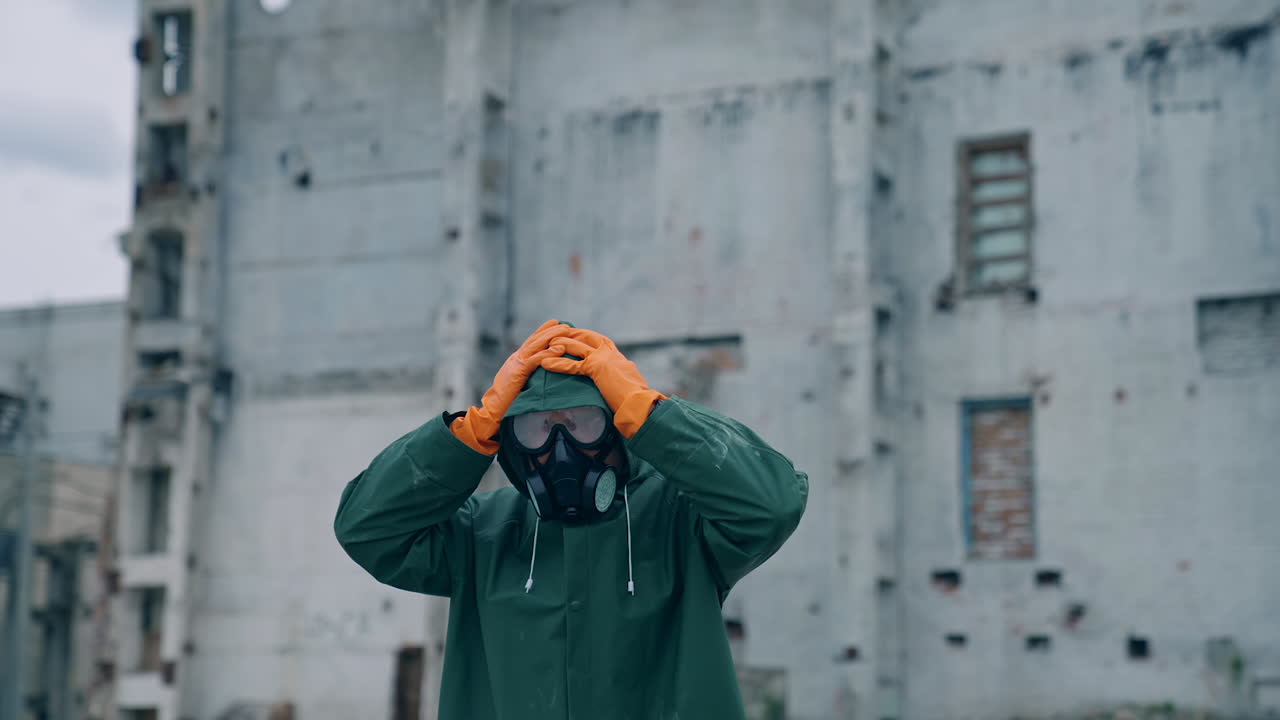 Atomic survivor in post apocalyptic setting. Portrait of guy in gas mask on the background of ruined abandoned building