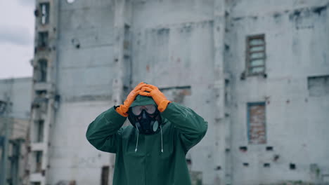 atomic survivor in post apocalyptic setting. portrait of guy in gas mask on the background of ruined abandoned building