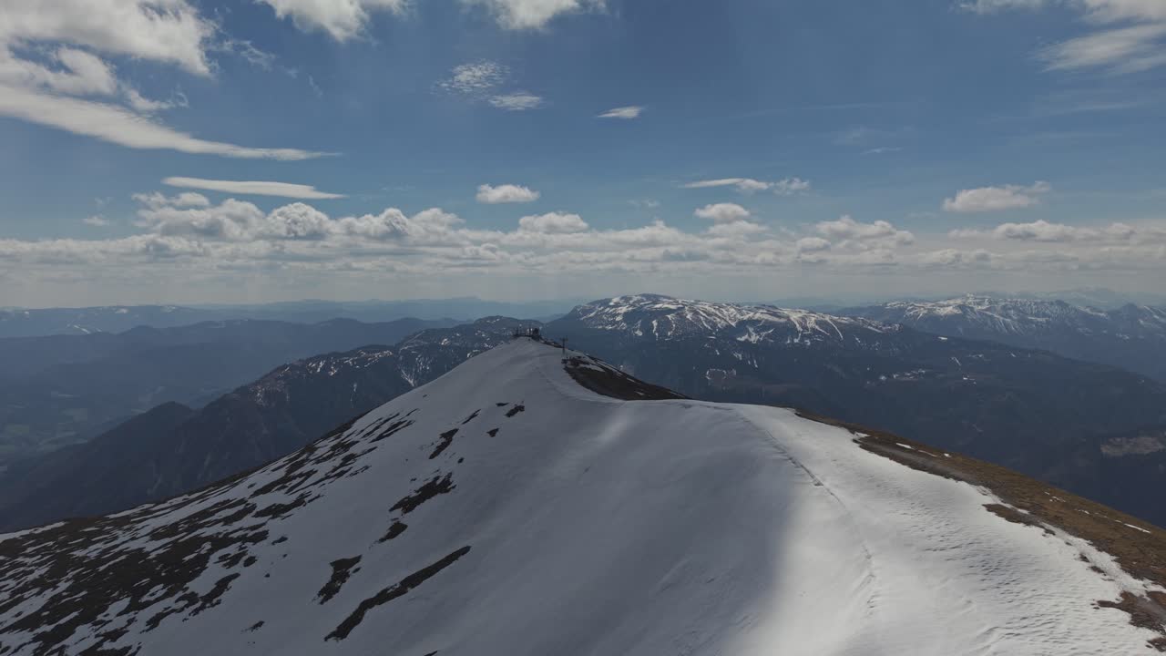 Una vista spettacolare di una cresta montuosa innevata che si estende in lontananza sotto un vasto cielo pieno di nuvole sparse.