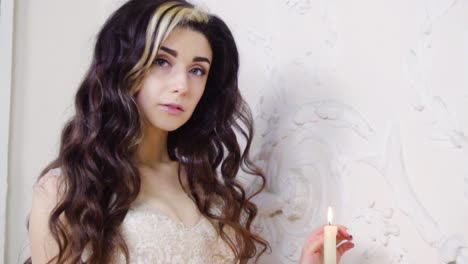 young brunette woman in long evening dress plays with candle