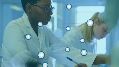Animation of network of medical icons over diverse female scientists working at laboratory