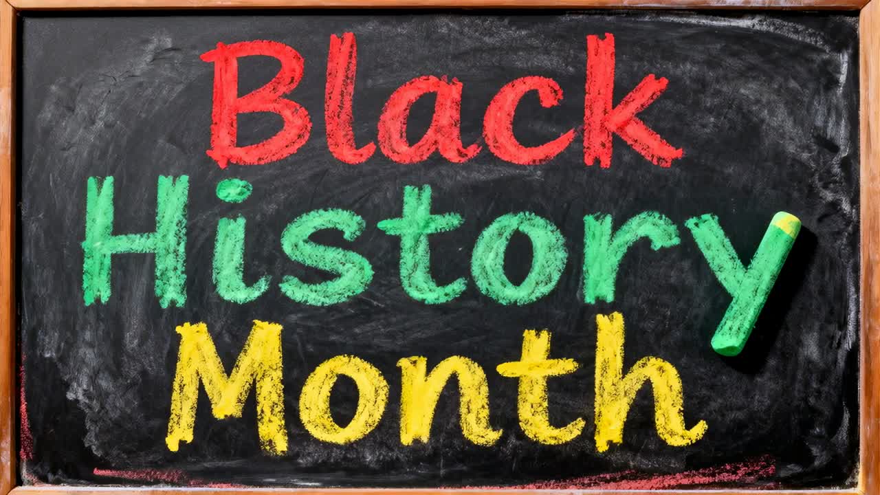 Rechterhand die binnenkomt en Black History Month-letters verfijnt op een schoolbord met een witte stift