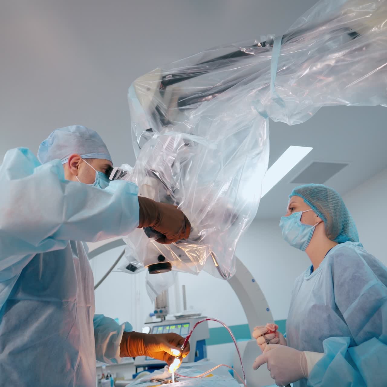 Professional doctor and a nurse perform a surgery. Surgeon uses modern medical equipment in the operating theater. Neurosurgery in clinic.