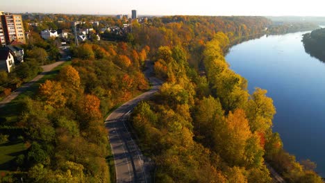 Toma-De-Drone-De-Un-Automóvil-Conduciendo-Por-Una-Carretera-Sinuosa-Junto-Al-Río-Nemunas-En-Kaunas,-Lituania,-Acercamiento