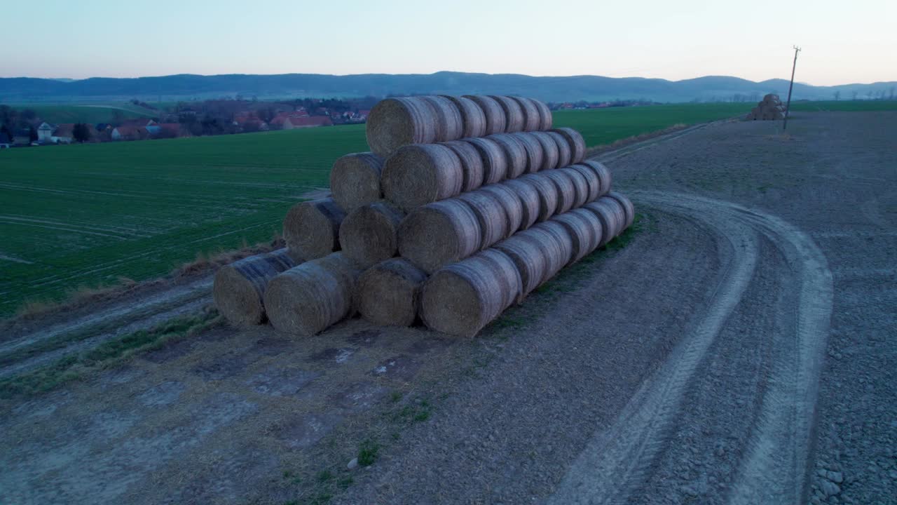 las balas de heno, apiladas en una pirámide, secas en el campo al atardecer.