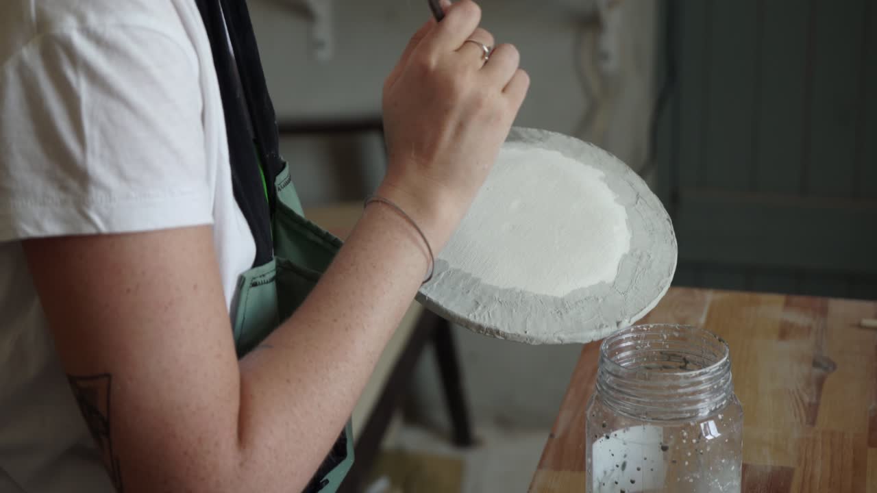 스튜디오에서 도자기 접시를 그리는 여자