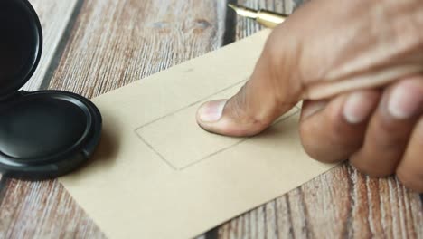 close up of a hand inking a stamp on an envelope