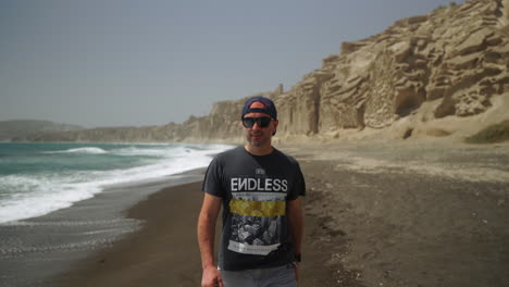 un hombre con gafas de sol camina por la playa de vlychada