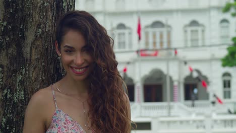 facial close up of a latina smiling while standing next to a tree and a castle in the background