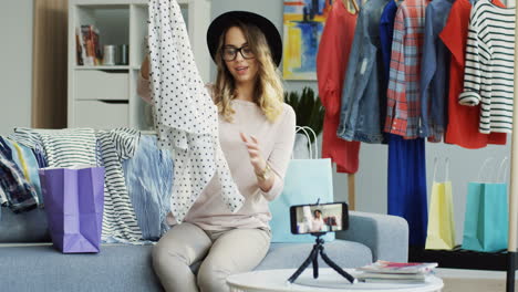 bastante joven bloguera de moda grabando un video y hablando de ropa nueva en casa