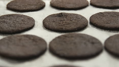 Circles-of-dark-cookie-dough-on-a-baking-tray-at-a-bakery