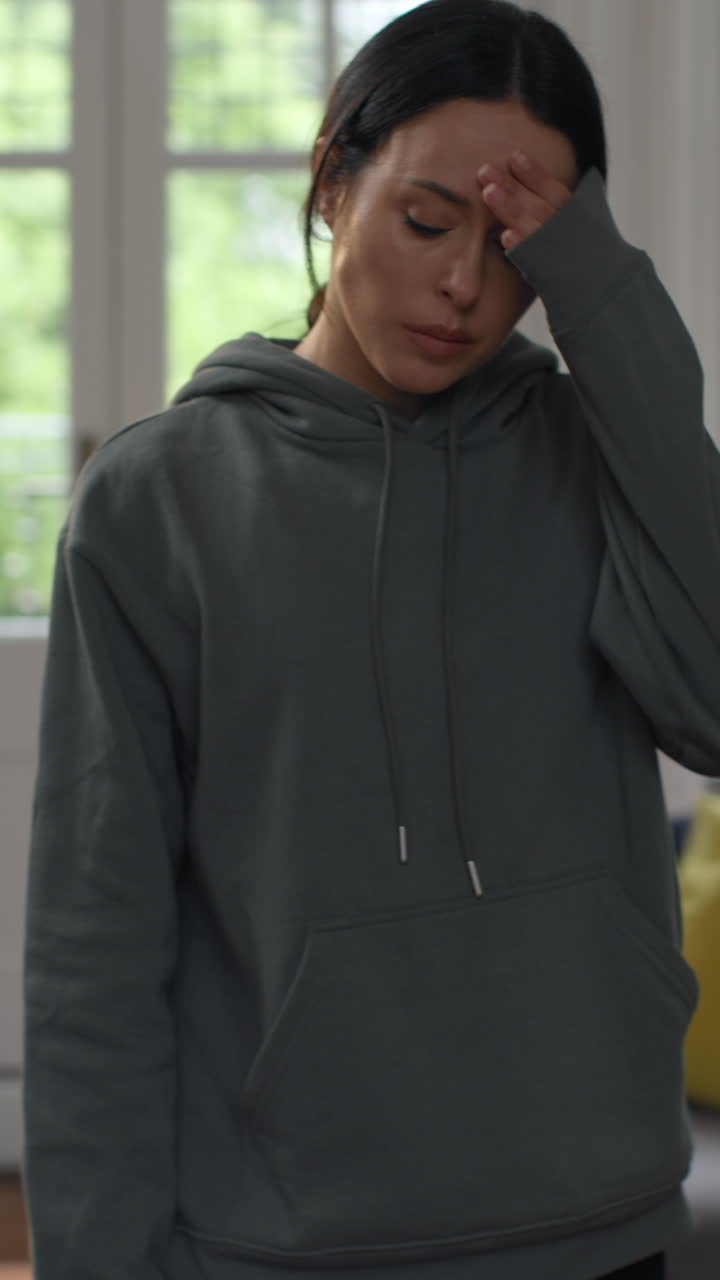 Vertical Video Of Anxious Woman At Home Comfort Eating Snack Before Sitting Indoors On Sofa And Working On Laptop