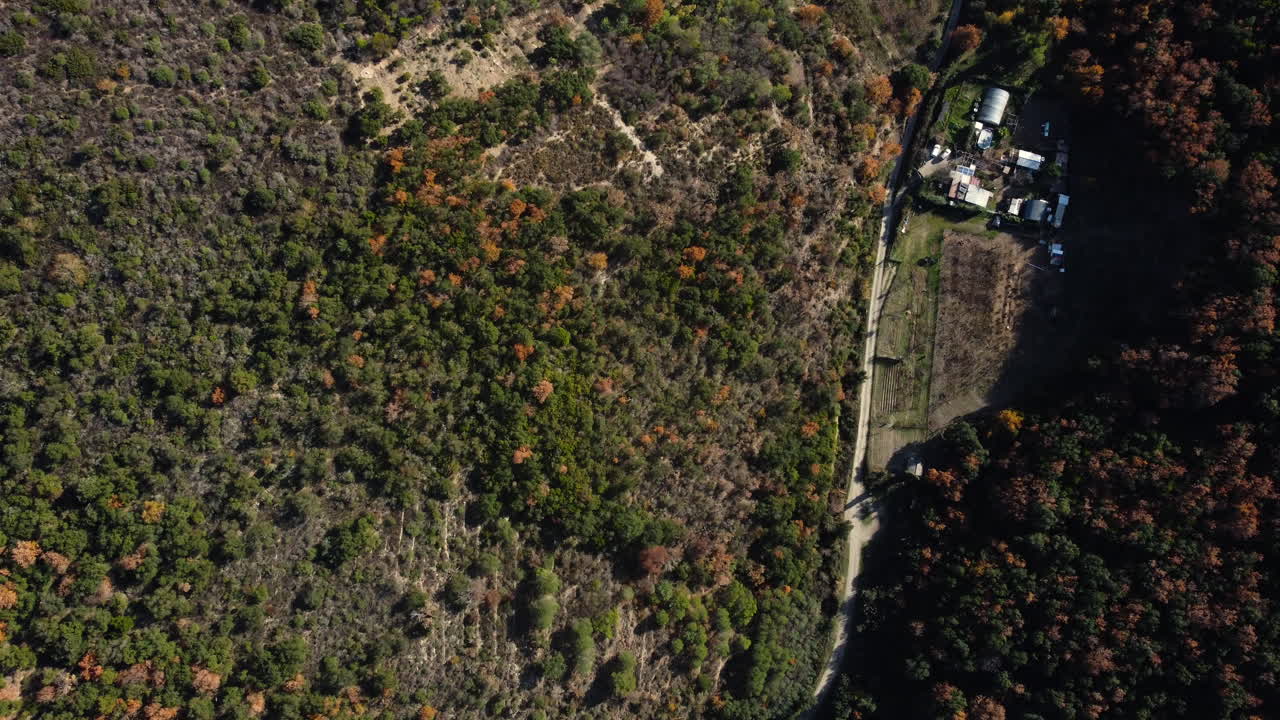 Aerial view of a rural landscape with forest, farmland, and buildings