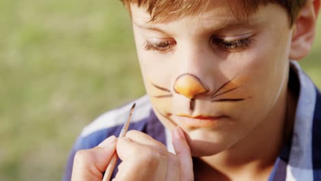 woman applying paint on boy nose 4k