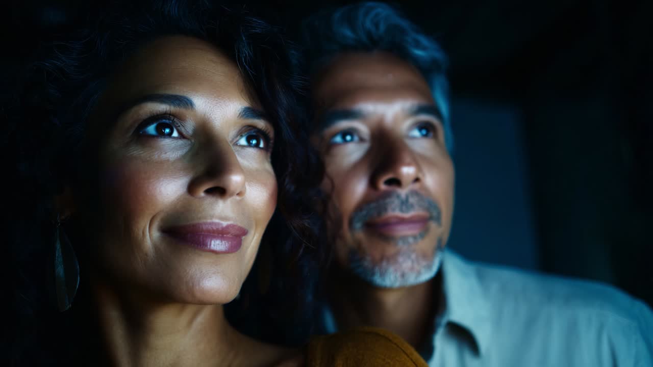 A Captivating Moment of Connection: A Couple Gazes Together at the Bright Light with Anticipation and Wonder, Their Faces Illuminated by the Glowing Radiance in a Darkened Room