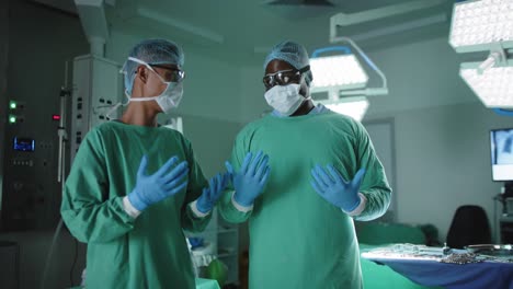 portrait of serious diverse male surgeons with medical gloves in operating room in slow motion