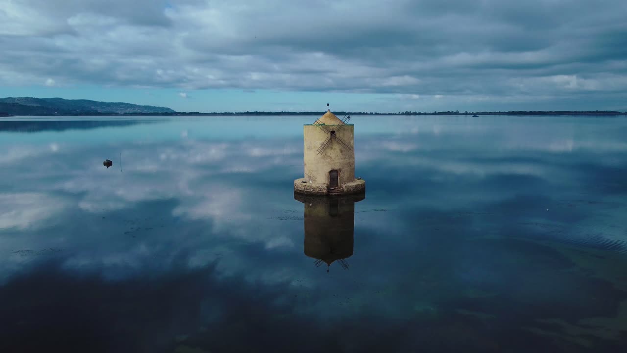 antiguo molino de viento español en la laguna en la ciudad de la isla orbetello cerca de monte argentario y el parque natural maremma en toscana, italia, con cielo azul y aguas azules tranquilas