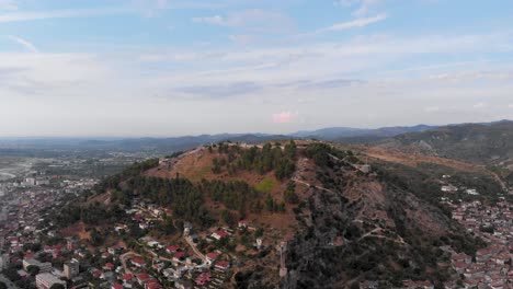 Atemberaubende-Luftdrohne-über-Der-Stadt-Berat-Mit-Burg-Und-Hügel-Bei-Klarem-Tag