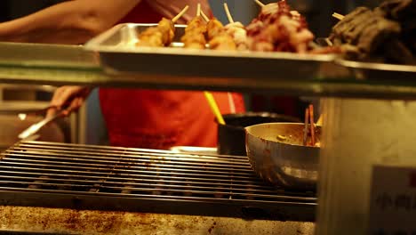vendor grilling skewers at a food stall