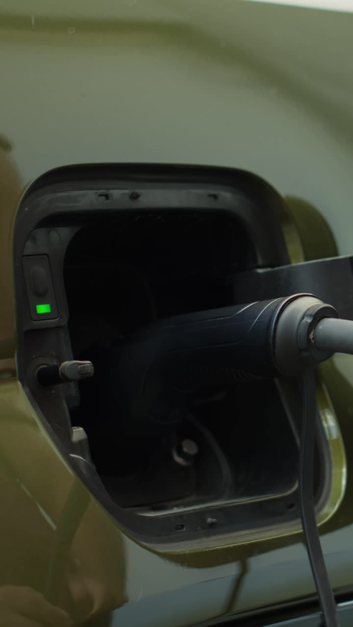 Elektrikli arabanın şarj portu kapağını açan çevre bilincine sahip sürücünün dikey yakın çekim videosu