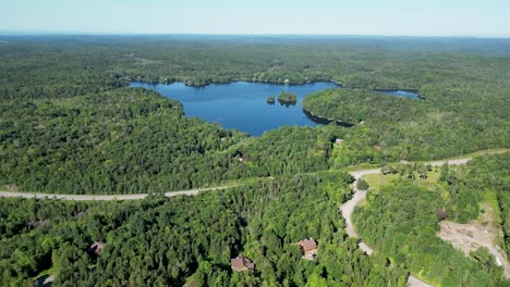 Disparo-De-Drones-En-Ascenso-Del-Lago-Que-Se-Revela-En-La-Distancia-Rodeado-De-Un-Bosque-Verde