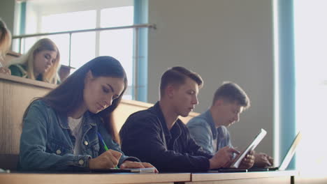 producción universitaria una gran audiencia de estudiantes escriben en los cuadernos de conferencias y computadoras portátiles.