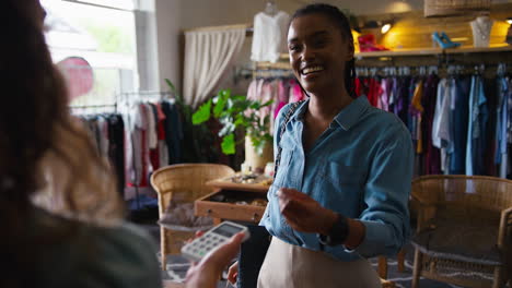 cliente femenino en una tienda de moda pagando por ropa con pago de tarjeta sin contacto