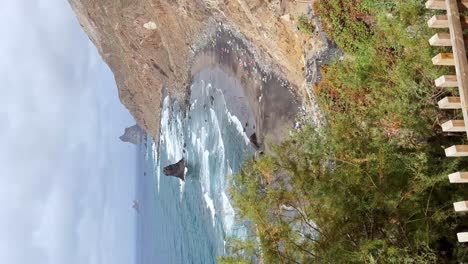 view of a cup of coffee in a viewpoint towards a paradisiacal black sand beach in tenerife