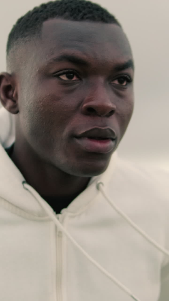 Young Black Man in White Hoodie Looking Focused Outdoors