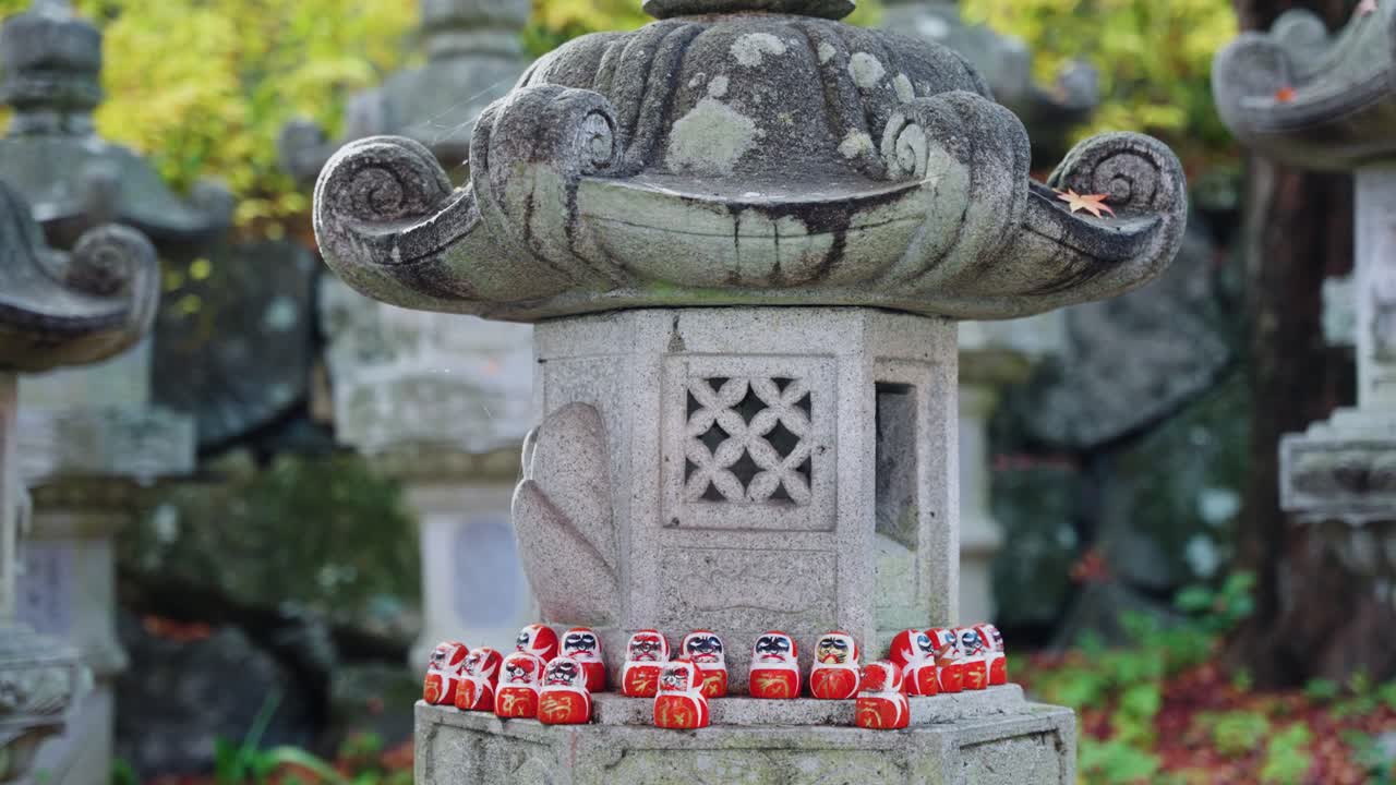 las muñecas daruma en la linterna de piedra del santuario en el templo de katsuoji, minoh, japón