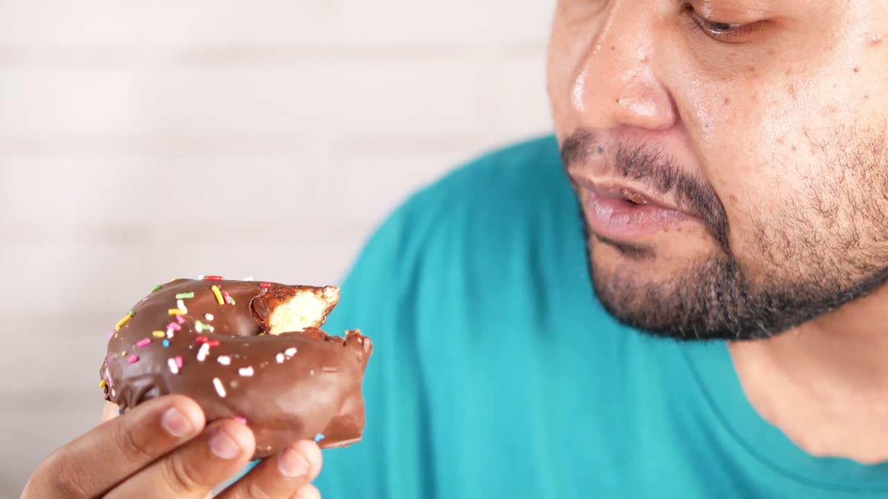 persona comiendo una rosquilla de chocolate