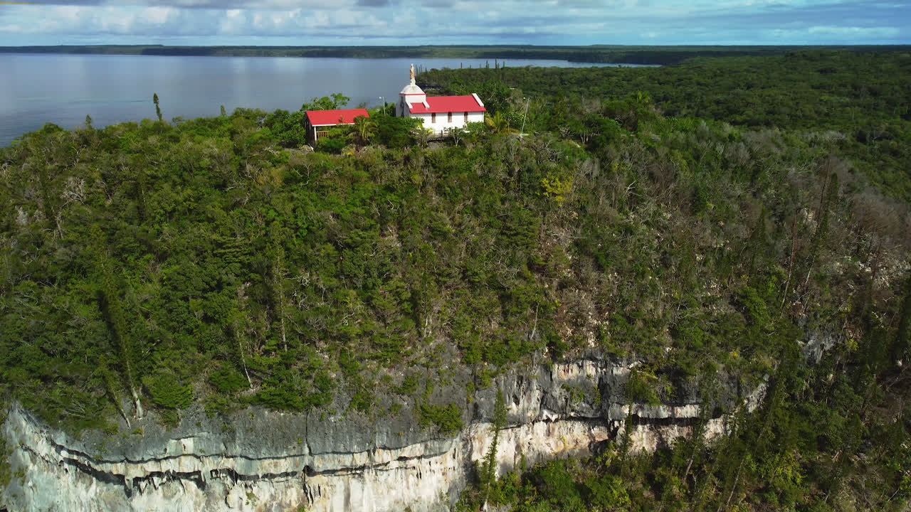 vista aérea de una capilla en la cima de una colina, en lifou, nueva caledonia - dando vueltas, tiro de drones