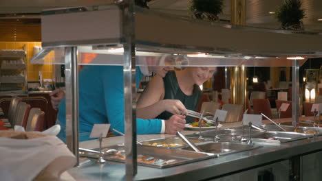 una pareja joven tomando comida en una cafetería de autoservicio.