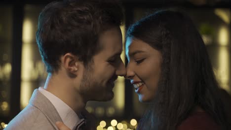 close-up view of a couple celebrating new year's eve party, they get closer and kiss while smiling