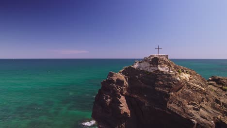 cross on top of a rock near the shore of spain