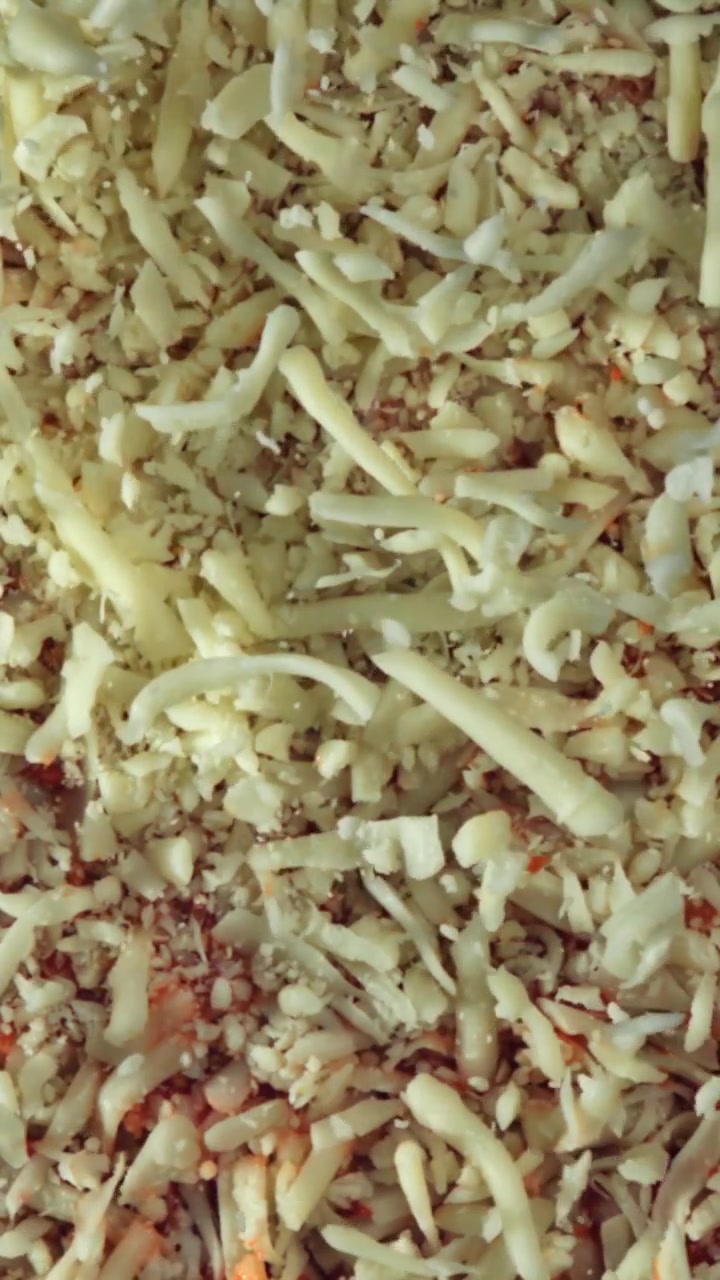 Primo piano di mozzarella grattugiata su pizza cruda