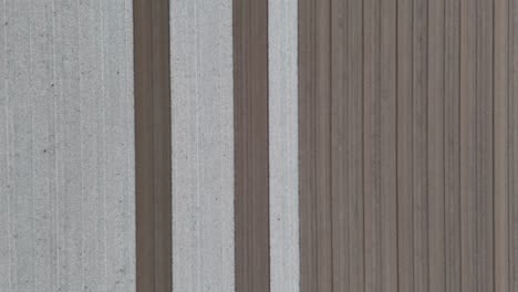 perpendicular overhead drone shot of alternating pale and dark furrows stretching across tilled field