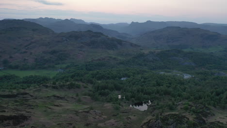 aerial footage moving slowly backwards from the langdale mountains to holme fell at sunset