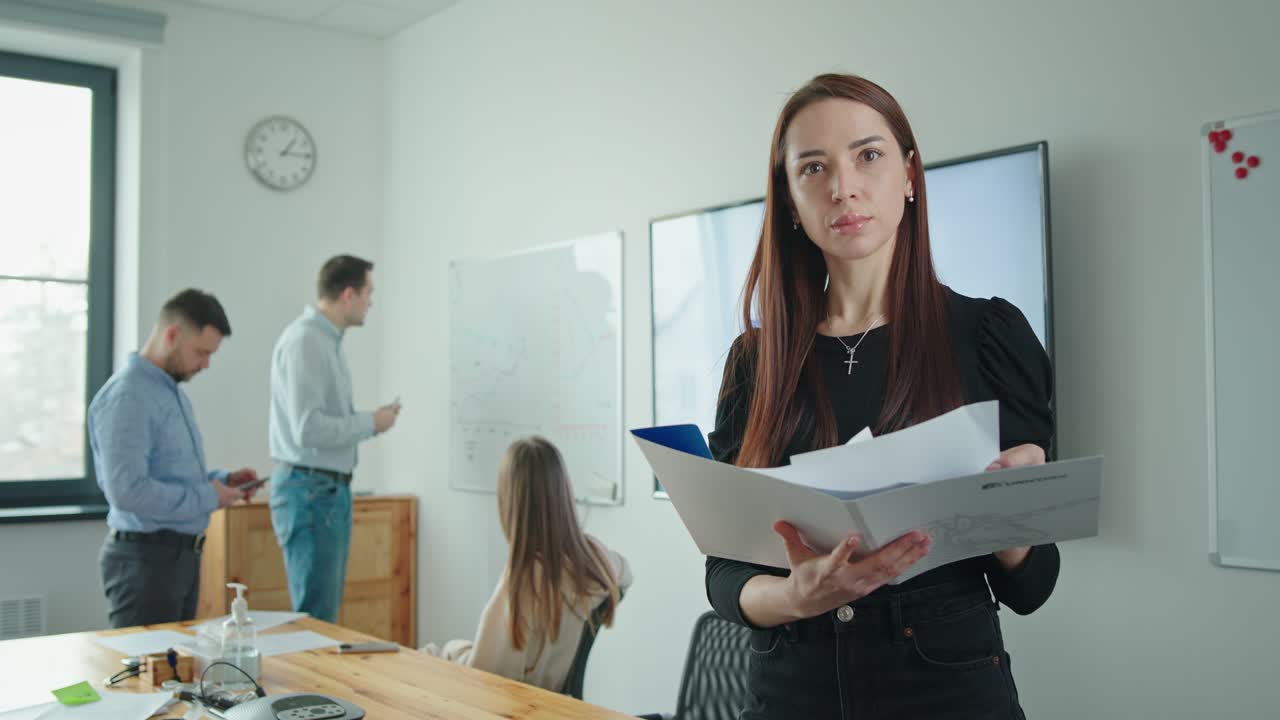 mujer leyendo documentos en la oficina con compañeros de trabajo