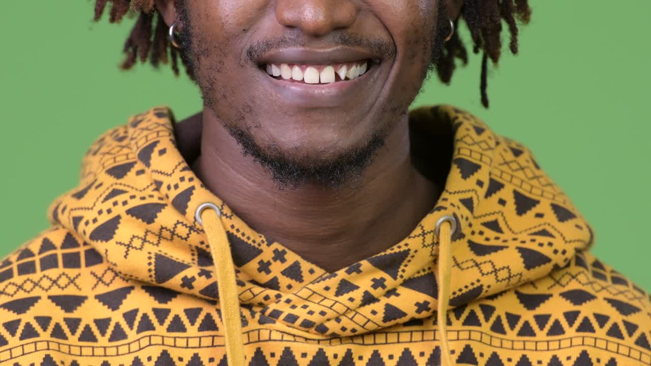 Mladý šťastný africký muž na zeleném pozadí