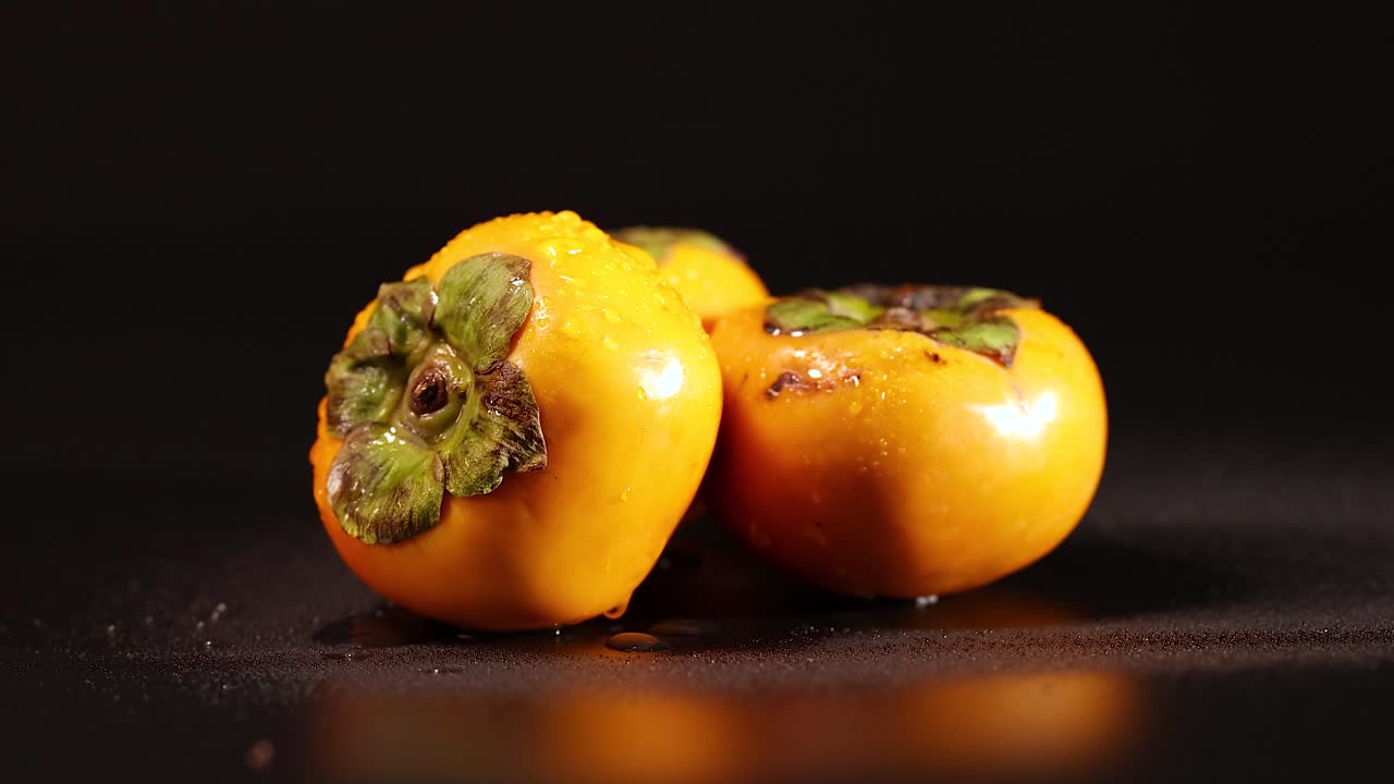 dos caqui descansando en un fondo oscuro