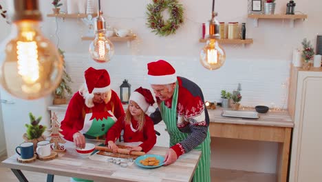 Grandparents-with-granddaughter-preparing,-cooking-homemade-cookie-roll-out-dough,-Christmas-kitchen